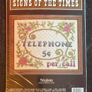 May include: A cross-stitch kit titled "Signs of the Times" featuring a framed design with the word "TELEPHONE" and "5¢ per call." The design includes floral accents in pink and green. The kit includes charted design, floss, and instructions.