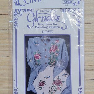 Puede incluir: Un paquete para un patrón de pintura fácil de planchar Glenda's para un diseño de rosa. El paquete muestra una camisa azul con un diseño de rosa y un chaleco blanco con un diseño de rosa. El paquete también incluye el texto "Glenda's Easy Iron-On Painting Pattern ROSE" y "GLENDA BETZ, Designer F-D-06".
