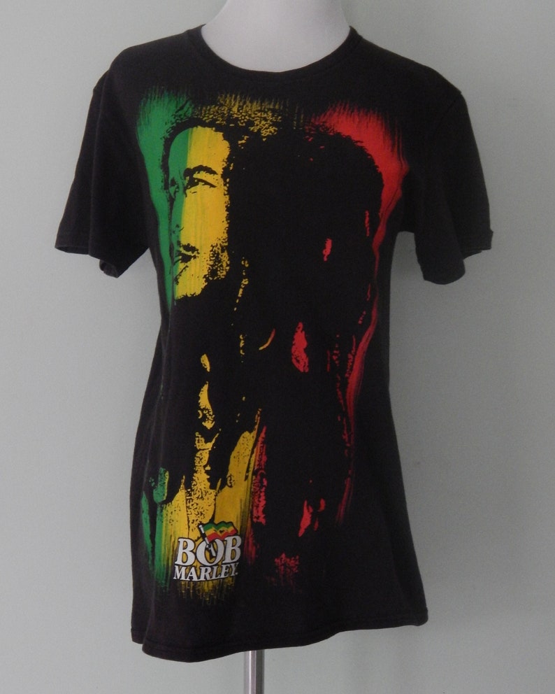 May include: Black t-shirt with a colorful image of Bob Marley. The image features a red, yellow, and green background with a silhouette of Bob Marley's face and hair.