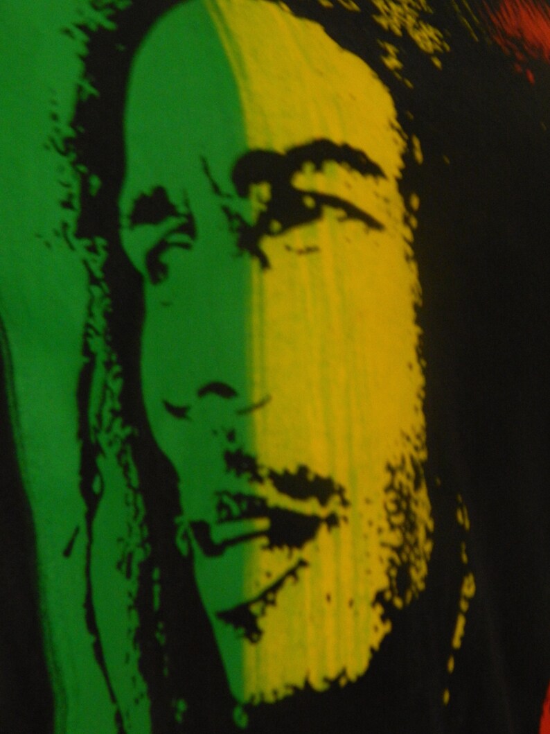May include: A black and white image of a person's face with green and yellow stripes behind them. The person has dreadlocks and a beard.