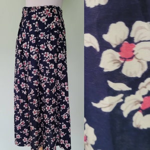 Può includere: Una lunga gonna blu navy con stampa floreale bianca e rosa. La gonna ha pieghe e un'alta vita.