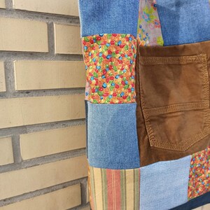Pu&ograve; includere: Una borsa tote patchwork con denim, velluto a coste e tessuti fantasia. La borsa combina vari colori e trame, tra cui denim blu, velluto a coste marrone e motivi floreali e a righe. Una tasca &egrave; visibile sul davanti.