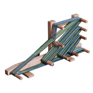 Könnte beinhalten: Ein Holzwebstuhl mit grün-blau gestreiftem Garn, das durch ihn gefädelt ist. Der Webstuhl hat eine Holzbasis und eine Reihe von Holzstiften.