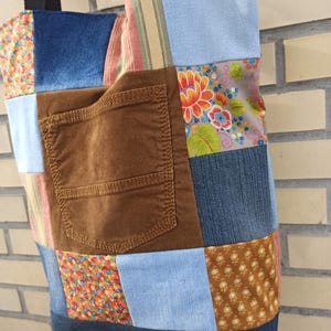 Pu&ograve; includere: Una borsa tote patchwork con una variet&agrave; di tessuti, tra cui denim, velluto a coste e stampe floreali. La borsa presenta una tasca in velluto a coste marrone e cinghie nere. Un accessorio unico e fatto a mano.