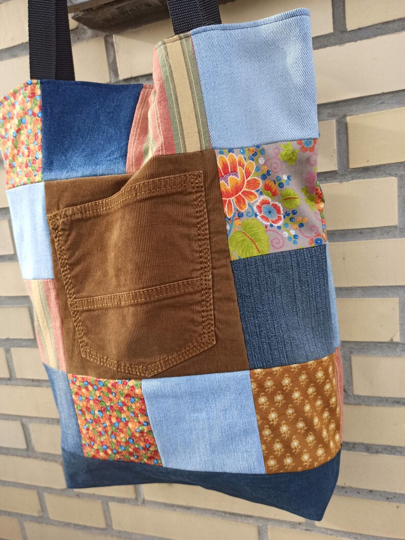 Pu&ograve; includere: Una borsa tote patchwork con una variet&agrave; di tessuti, tra cui denim, velluto a coste e stampe floreali. La borsa presenta una tasca in velluto a coste marrone e cinghie nere. Un accessorio unico e fatto a mano.