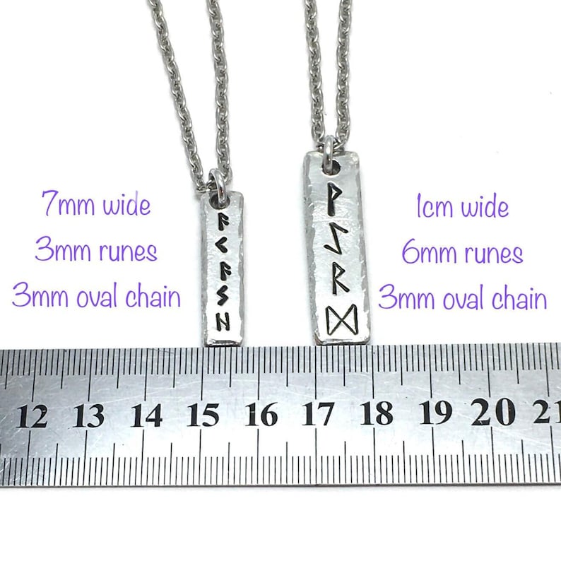 Stainless steel ruler with two pewter rune pendants side by side to show size comparison between 7mm and 1cm wide pendants. Pendants are stamped vertically with 3mm and 6mm runes to show size comparison. Displayed on white background with 3mm chains