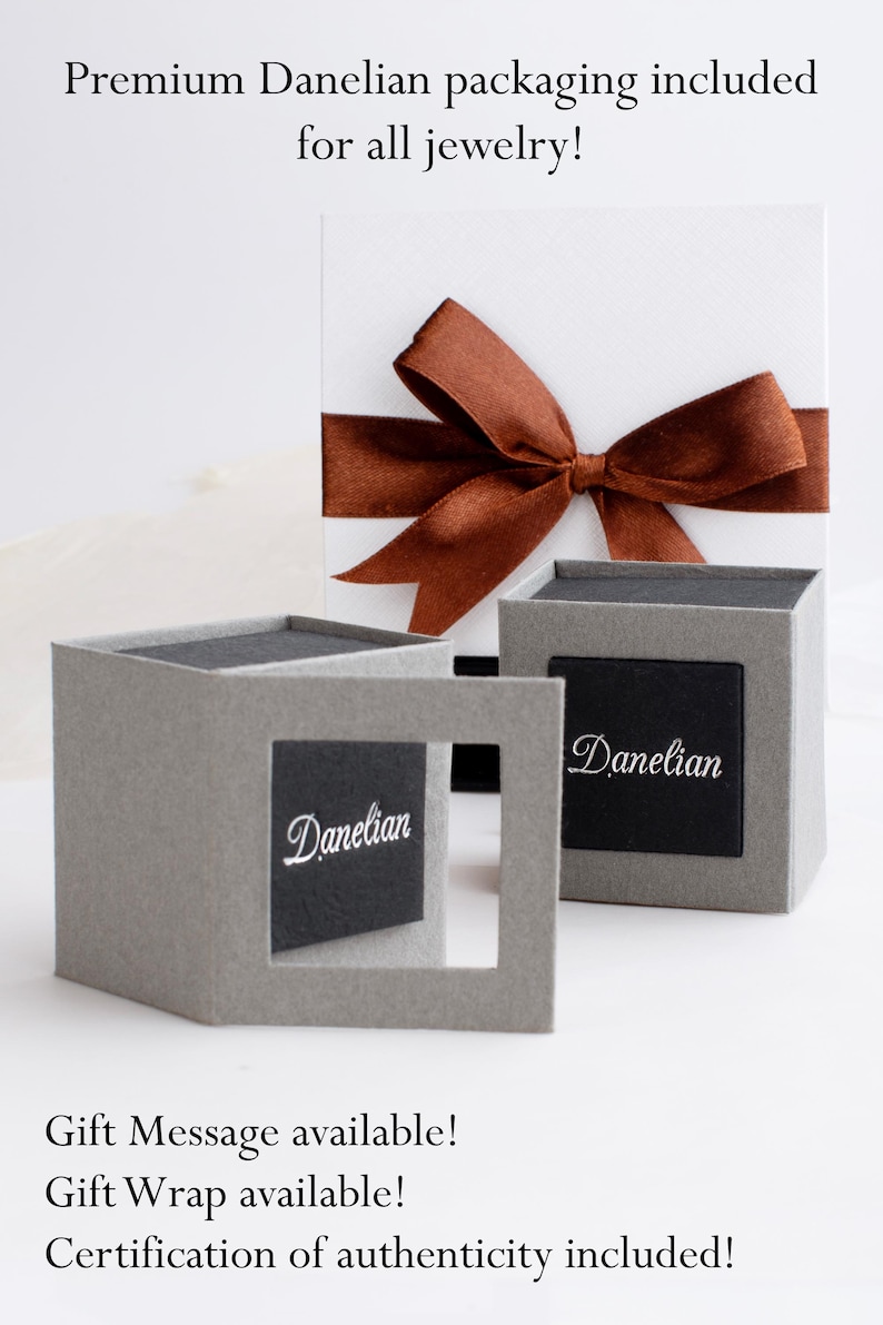 Puede incluir: Imagen de embalaje de joyas. La imagen muestra una caja de regalo blanca con una cinta marr&oacute;n y dos cajas grises con la palabra "Danelian". El texto de la imagen dice "&iexcl;Embalaje Premium Danelian incluido para todas las joyas!"