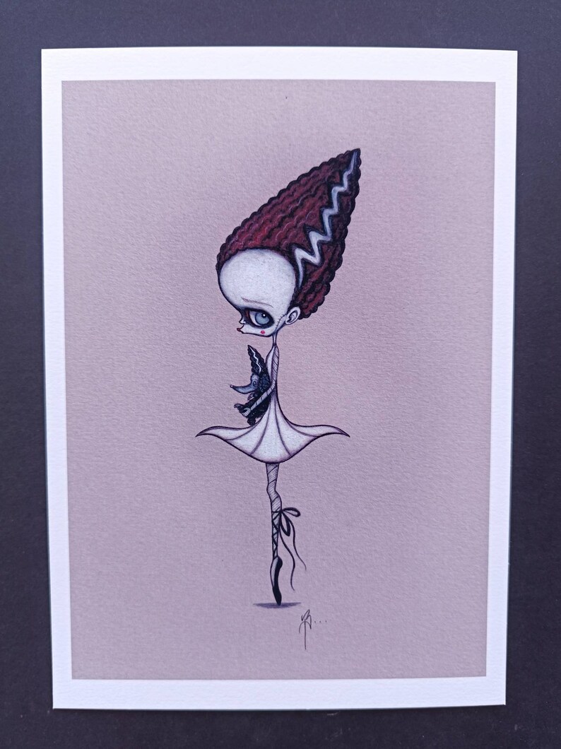 May include: A black and white illustration of a Frankenstein-inspired ballerina holding a small black bird. The ballerina is wearing a white dress and black shoes. The background is a light pink color.
