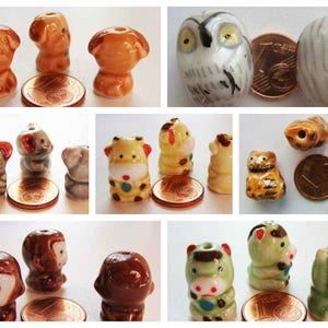 Pode incluir: Conjunto de figuras de animais de cerâmica, incluindo um cão, um gato, uma coruja, uma girafa, um macaco e uma vaca. As figuras são pintadas em várias cores e têm detalhes elaborados.