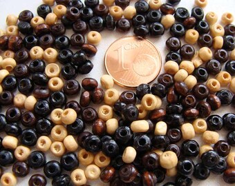 Könnte beinhalten: Nahaufnahme von kleinen Holzperlen in Schwarz, Braun und Naturtönen. Eine 1-Cent-Münze dient als Größenvergleich. Die Perlen sind für Schmuckherstellung oder Bastelprojekte geeignet. Die Perlen haben einen Durchmesser von ca. 0,5 cm.