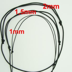 Peut inclure: Trois cordons noirs de différentes épaisseurs, 1 mm, 1,5 mm et 2 mm, sont disposés sur une surface blanche.