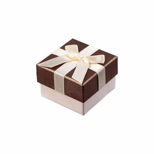 May include: A square gift box with a dark brown lid and a light cream-colored base. The lid is decorated with a smooth, light cream-colored ribbon tied into a bow centered on the top surface, creating a clean and structured presentation.