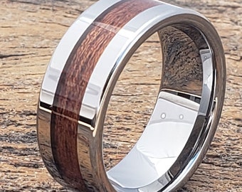 May include: A silver tungsten carbide ring with a brown wood inlay. The ring is beveled and has a polished finish.