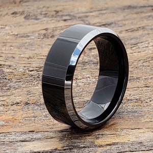 May include: A black beveled tungsten carbide ring. The ring has a polished finish and a beveled edge.