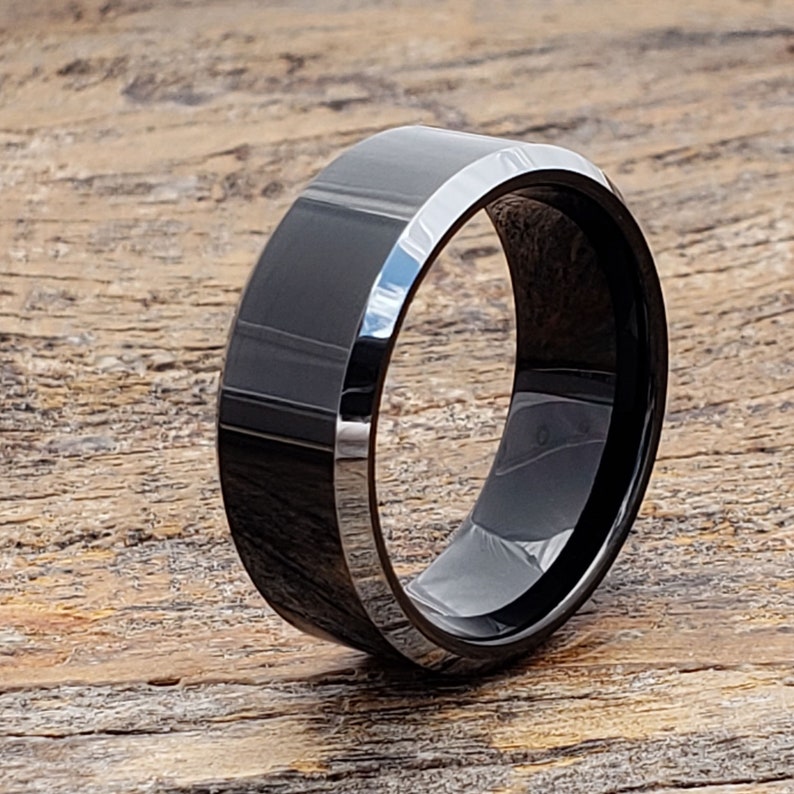 May include: A black beveled tungsten carbide ring. The ring has a polished finish and a beveled edge.