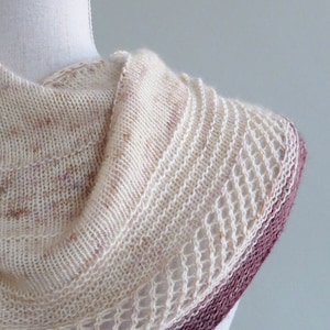 May include: A white knitted cowl with a burgundy trim. The cowl is made with a delicate stitch pattern and has a soft, drapey texture.