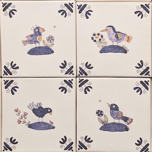 May include: Sixteen square ceramic tiles featuring hand-drawn bird illustrations. Each bird sits on a small blue mound, with flowers and insects. The tiles have a cream background with dark blue corner designs.