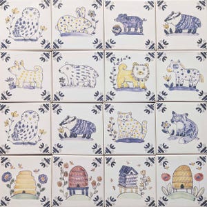May include: Sixteen square ceramic tiles with hand-painted animal and beehive designs. The tiles depict an owl, rabbit, and lion, among others, in a folk art style. The color scheme includes blue, yellow, and white. Each tile has a decorative border.