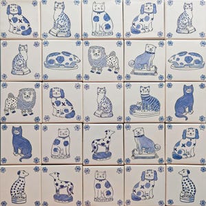 May include: A collection of 24 blue and white ceramic tiles featuring various animal illustrations. Each tile depicts a different animal, including cats, dogs, lions, and a rabbit. The tiles are all square and have a white background with blue floral accents.