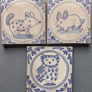 May include: A set of three ceramic mugs with a speckled, matte finish. The mugs are in shades of cream, light gray, and dark gray. Each mug has a simple, minimalist design and a rounded handle.