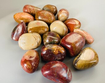 May include: A collection of tumbled stones in shades of brown, red, and cream. The stones are smooth and polished, with a variety of patterns and textures.