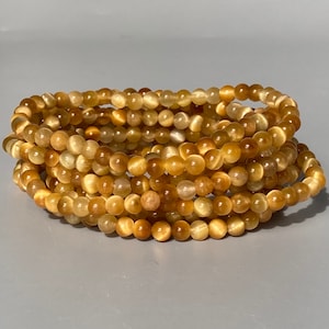 May include: A stack of golden tiger's eye bead bracelets. The beads are round and have a subtle shimmer.