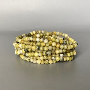 May include: A stack of green and yellow gemstone bracelets. The bracelets are made of small, round beads.
