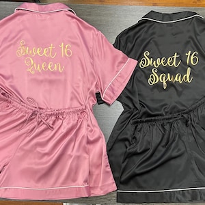 May include: Two matching pajama sets. One is pink with "Sweet 16 Queen" in gold script, the other is black with "Sweet 16 Squad" in gold script. Both sets include a short-sleeved top and shorts with white trim.