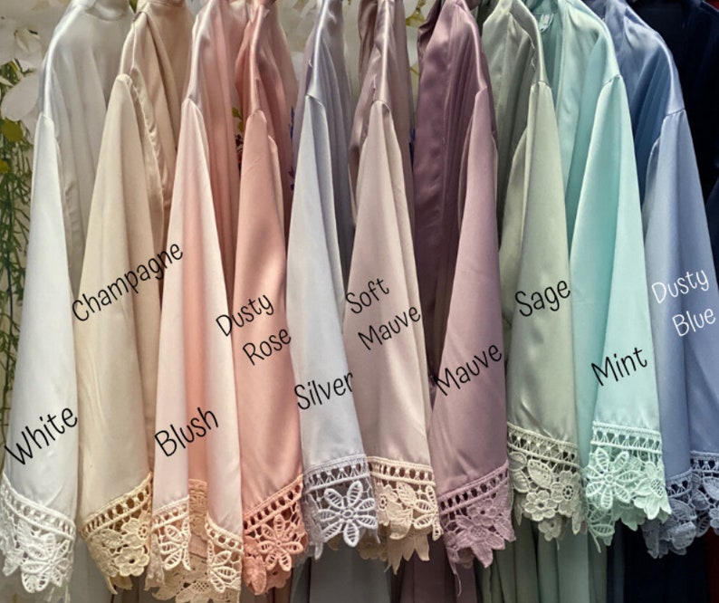 Peut inclure: Dix robes en satin de diff&eacute;rentes couleurs, dont blanc, champagne, blush, rose poudr&eacute;, argent, mauve doux, mauve, sauge, menthe et bleu poussi&eacute;reux. Chaque robe est orn&eacute;e d'une bordure en dentelle et est suspendue &agrave; un cintre.