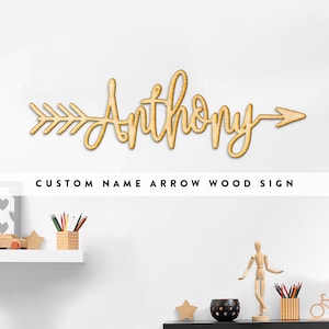 May include: A wooden sign in the shape of an arrow with the name "Anthony" in a cursive font. The sign is light brown and has the text "CUSTOM NAME ARROW WOOD SIGN" below it.