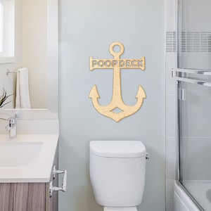 K&ouml;nnte beinhalten: Ein Anker aus Holz mit den ausgeschnittenen Worten "Poop Deck". Der Anker ist an einer wei&szlig;en Badezimmerwand &uuml;ber einer wei&szlig;en Toilette angebracht.