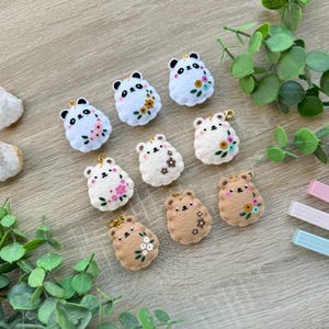 Peut inclure: Neuf porte-clés en feutre en forme d'animaux avec broderie florale. Les porte-clés sont en trois couleurs : blanc, crème et marron. Chaque porte-clés présente un visage d'animal différent avec des fleurs brodées.