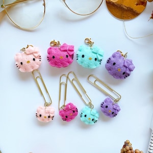 May include: Set of six colorful felt Hello Kitty bookmark clips with gold metal clips. Each clip features a different color Hello Kitty with a bow.