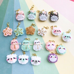May include: A collection of 18 handmade felt charms featuring various winter-themed designs, including snowmen, snowflakes, and animals. The charms are attached to gold jump rings and are perfect for adding a touch of whimsy to bags, keychains, or other accessories.