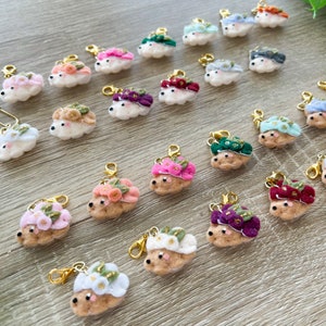 Peut inclure: Une collection de 20 breloques en feutre en forme de hérisson avec des couronnes de fleurs de différentes couleurs. Chaque breloque a une boucle dorée pour l'attacher à un porte-clés ou à un sac.
