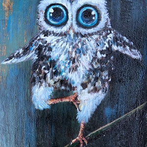 Puede incluir: Una pintura caprichosa de un b&uacute;ho con grandes ojos azul brillante. El b&uacute;ho est&aacute; posado en una rama, con las alas ligeramente extendidas. La obra presenta un fondo texturizado con tonos de azul y negro, creando un contraste llamativo.