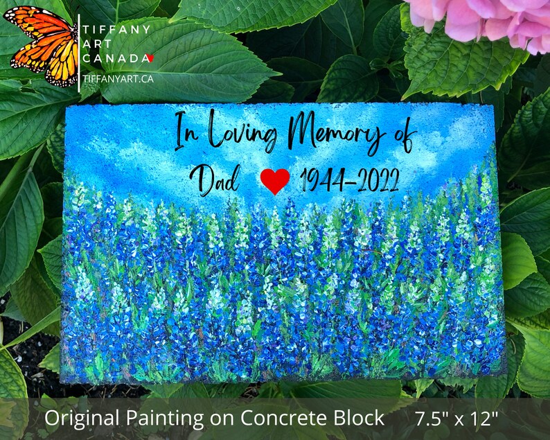 May include: A hand-painted concrete block memorial with a bluebonnet flower field, a blue sky, and the text "In Loving Memory of Dad 1944-2022". The block measures 7.5 inches by 12 inches.