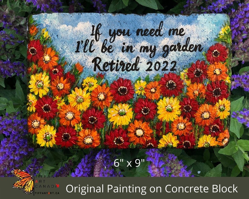May include: A 6-inch by 9-inch concrete block painted with a garden scene of red, orange, and yellow flowers. The text "If you need me I'll be in my garden Retired 2022" is painted on the block.