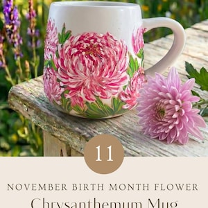 May include: A white ceramic mug featuring hand-painted pink chrysanthemum flowers with green leaves. The mug includes text that reads 11 NOVEMBER BIRTH MONTH FLOWER Chrysanthemum Mug HAND PAINTED WITH LOVE PERSONALIZED GIFT - ADD YOUR CUSTOM TEXT.