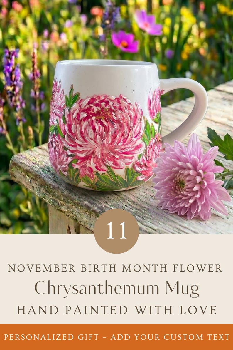 May include: A white ceramic mug featuring hand-painted pink chrysanthemum flowers with green leaves. The mug includes text that reads 11 NOVEMBER BIRTH MONTH FLOWER Chrysanthemum Mug HAND PAINTED WITH LOVE PERSONALIZED GIFT - ADD YOUR CUSTOM TEXT.