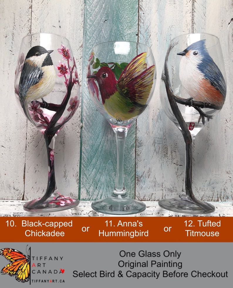 May include: Three hand-painted wine glasses featuring different birds: a Black-capped Chickadee, an Anna's Hummingbird, and a Tufted Titmouse. Each glass has a unique bird design with floral or branch accents. The text on the image says "One Glass Only, Original Painting."