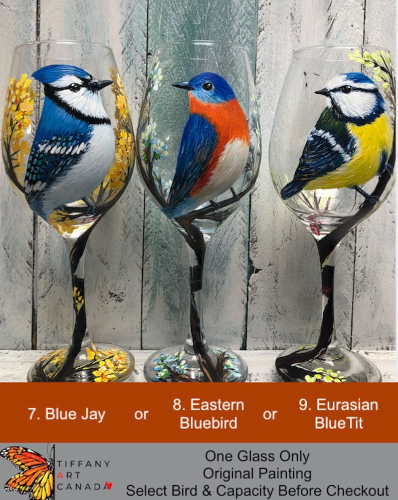May include: Three hand-painted wine glasses featuring detailed bird portraits: a Blue Jay, an Eastern Bluebird, and a Eurasian Blue Tit. Each glass showcases a different bird species with vibrant colors and delicate floral accents. The text on the image says "One Glass Only, Original Painting."