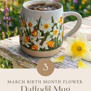 May include: A ceramic mug featuring a hand-painted design of white and yellow daffodils with green stems. The mug contains dark liquid and is accompanied by a single yellow daffodil flower. Text on the image reads: 3 MARCH BIRTH MONTH FLOWER Daffodil Mug HAND PAINTED WITH LOVE PERSONALIZED GIFT - ADD YOUR CUSTOM TEXT.