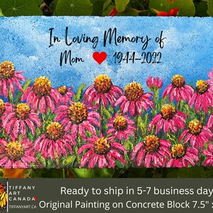 May include: A hand-painted concrete block memorial with a pink flower field and the text "In Loving Memory of Mom 1944-2022".