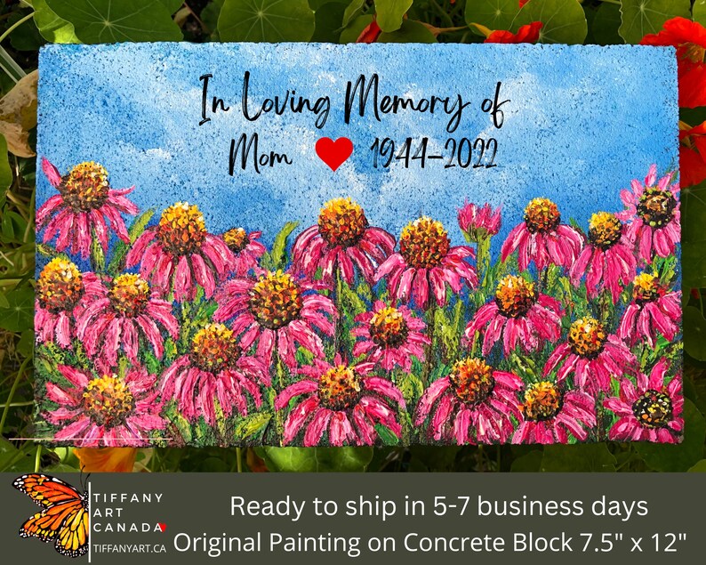 May include: A hand-painted concrete block memorial with a pink flower field and the text "In Loving Memory of Mom 1944-2022".