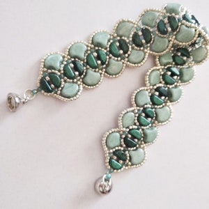 Op de afbeelding: Een groene en zilveren kralen armband met een gegolfd ontwerp. De armband heeft aan beide uiteinden een zilveren sluiting.