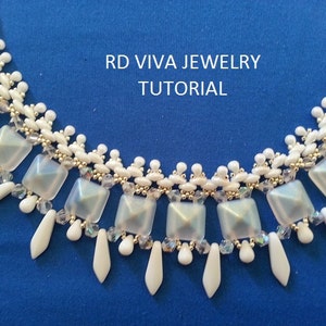 Pu&ograve; includere: Una collana di perline bianche con un design geometrico che presenta perline quadrate e a forma di goccia. La collana ha una chiusura in metallo argentato ed &egrave; etichettata "RD VIVA JEWELRY TUTORIAL".