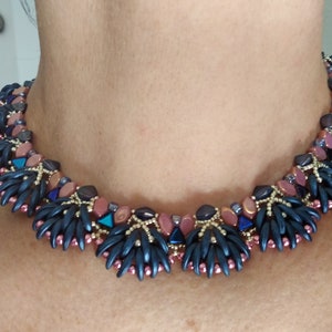 May include: A beaded necklace with a geometric design featuring dark blue, pink, and gold beads.