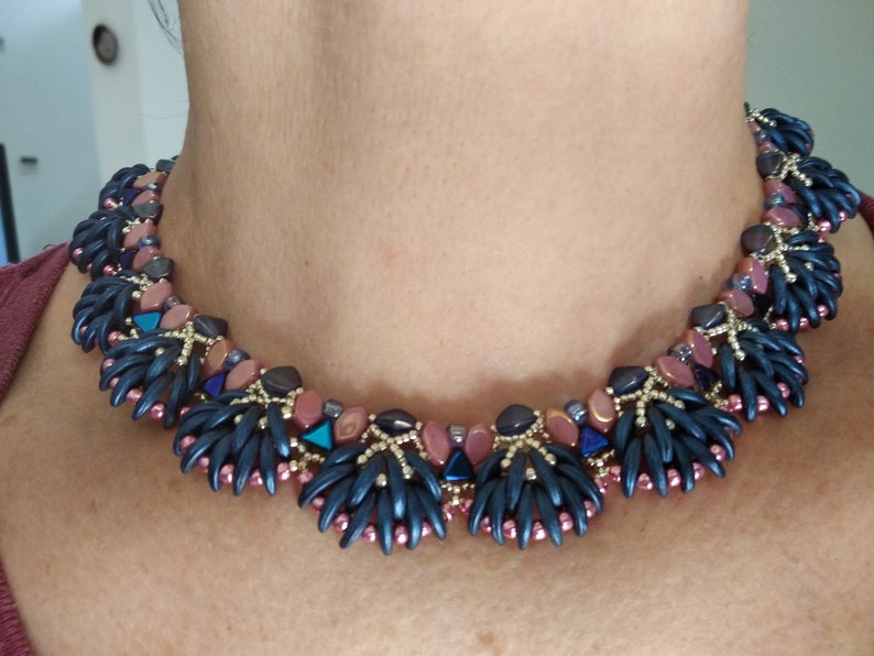 May include: A beaded necklace with a geometric design featuring dark blue, pink, and gold beads.