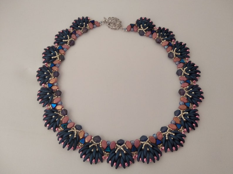 May include: A dark blue and pink beaded necklace with a silver clasp. The necklace features a repeating pattern of small, dark blue beads and larger, pink beads.